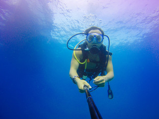 Underwater scuba diving selfie shot with selfie stick. Deep blue sea. Wide angle shot.