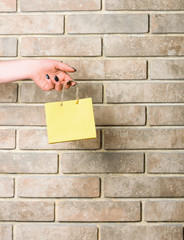 yellow shopping bag in female hand on brick wall