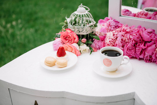 beautiful pink flowers and cup of coffee standing on a white tab