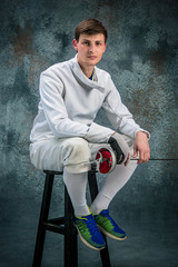 The man wearing fencing suit with sword against gray