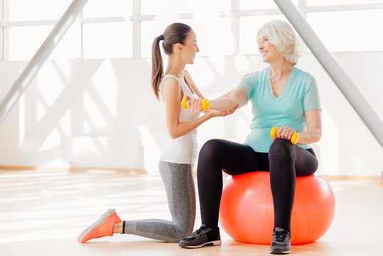 Positive elderly woman exercising with dumbbells