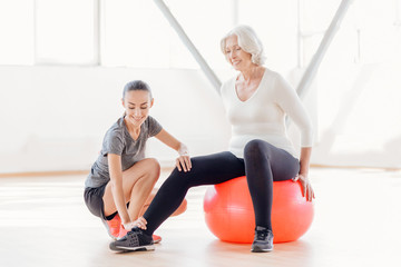 Joyful elderly woman sitting on the fitness ball