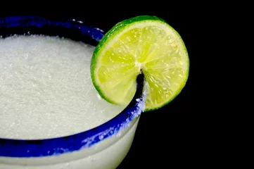 Poster Blue rimmed glass with margarita and lime slice against a black background © jlmcanally