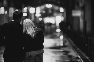 beautiful and young couple walking on the wet asphalt