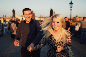 young woman and man walking on the old street at sunset