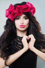 Naklejka premium Beautiful Model Making a Heart and Blowing a Kiss. Brunette Woman with Curly Hair and Makeup, Love Concept