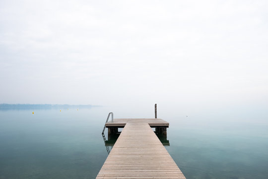 Pontile vuoto sul lago in una giornata nebbiosa