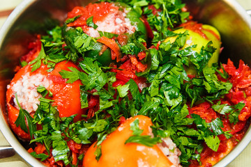 raw stuffed pepper with greens in pan.