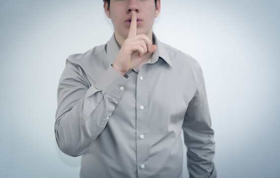 Young man gesturing hush with finger on lips