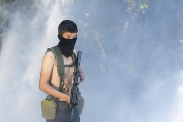 Man in mask holding rifle against smoke - 137089032