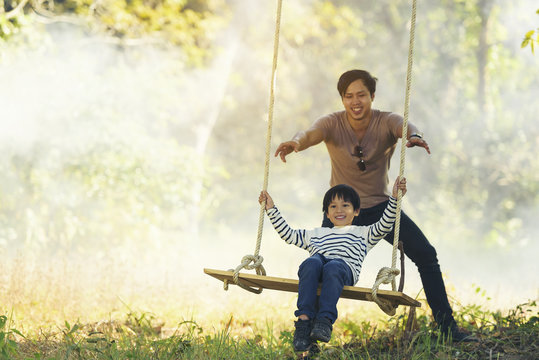 Happy Asian Family On A Swing At Field In The Countryside. Smile With Family On Thailand 2017