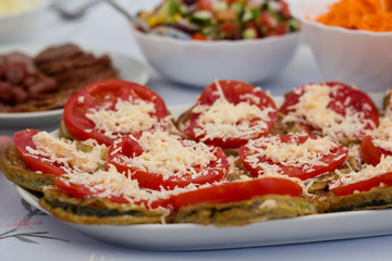 Meal of tomatoes and zucchini with cheese on table