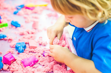 Boy playing with kinetic sand in preschool. The development of fine motor concept. Creativity Game...