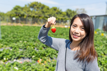 Young Woman holding strawberry in the garden