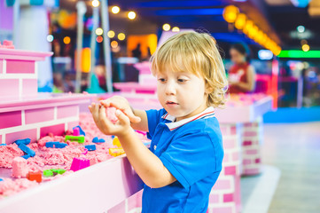 Boy playing with kinetic sand in preschool. The development of fine motor concept. Creativity Game...