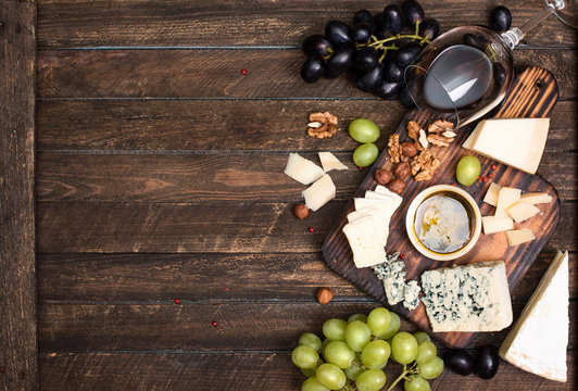 Red wine, grape, cheese, honey and nuts over rustic wooden table. Top view with copy space.