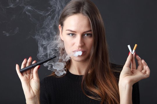 Junge schöne Frau mit E-Zigarette und normaler Zigarette