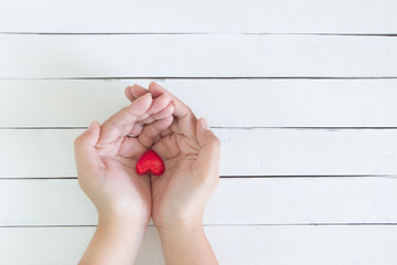 Hands giving a red heart on white wood background, Love concept