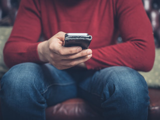 Man with smartphone sitting on sofa