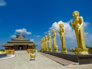 Golden Temple Palace Relic House with series of golden Standing Buddha Statues bodhi tree lion statue scluptures with blue sky and clouds at Nelligala International Buddhist Center Kandy, Sri Lanka