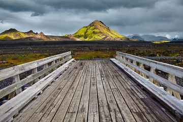Wooden bridge over a river in ICELAND. Beautiful Icelandic landscape with mountains, sky and...