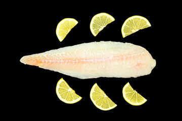 Frozen fish isolated on black background with lemon slices.