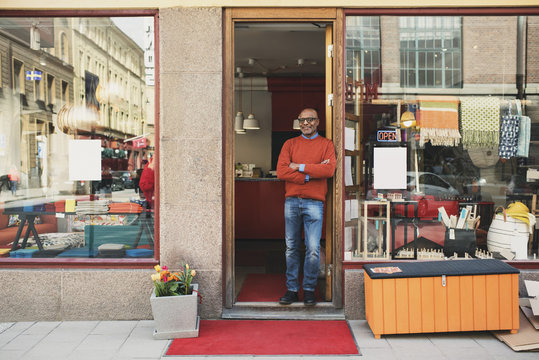 Portrait of boutique owner standing in door of his store