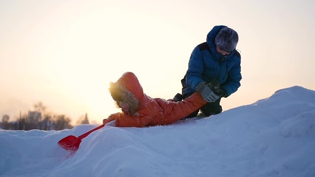 children playing in winter on a snowy mountain against the sky