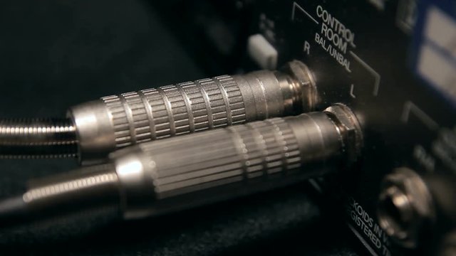 Inserting two XLR male cords into a audio mixer closeup.