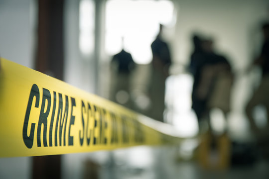 crime scene tape with blurred forensic law enforcement background in cinematic tone