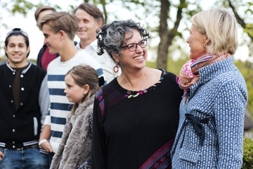 Happy multi-ethnic women talking while standing with friends and family in yard