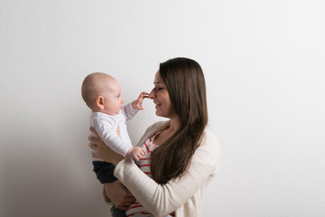 Beautiful mother holding baby son in her arms. Studio shot.