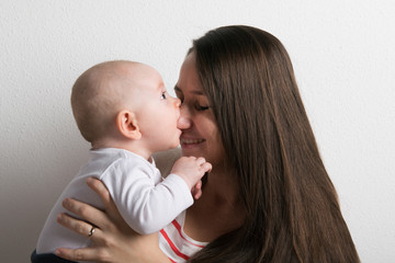 Beautiful mother holding baby son in her arms. Studio shot.