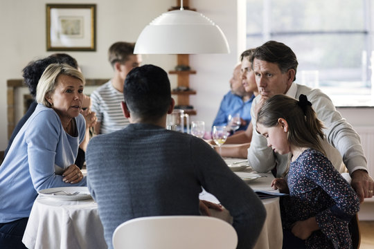 Multi-ethnic friends and family talking at dining table in dinner party