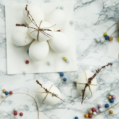 Easter eggs decorated with dried flowers with twine on a marble table. with colored jelly beans French - sweetness