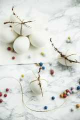 Easter eggs decorated with dried flowers with twine on a marble table. with colored jelly beans French - sweetness