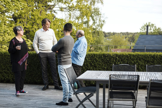 Multi-ethnic friends talking while standing by table in yard