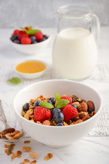 Homemade granola with fresh berries on white wooden background, selective focus