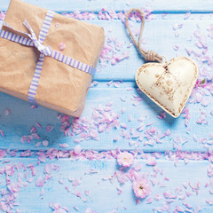 Box with present and decorative  heart on blue wooden planks.
