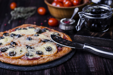 pizza with salami, mozzarella, olives and basil