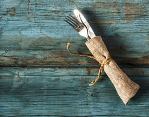 fork and knife in napkin on wood