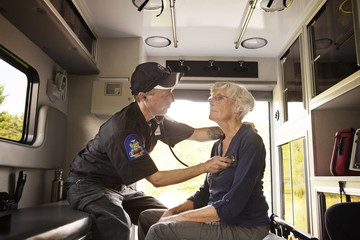 Paramedic using stethoscope on elderly patient