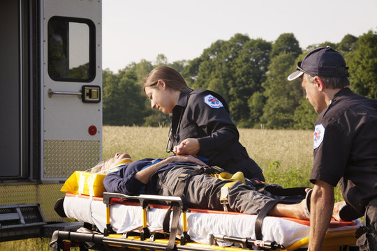 Paramedic comforting injured woman on gurney