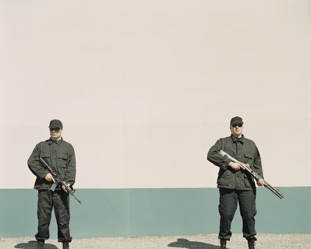 Two men wearing special forces uniforms, holding high powered guns