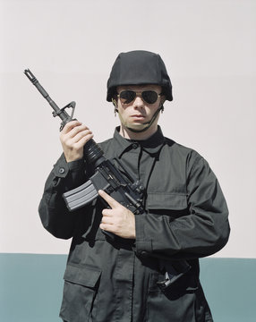Man wearing special forces uniform and holding high powered semi-automatic rifle