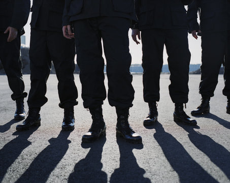 Low angle view of row of men wearing military uniforms, casting shadows