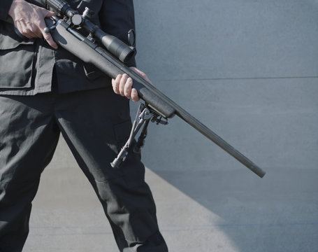 Man in armed forces holding high powered sniper riifle