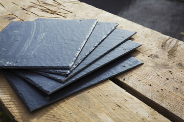 A pile of slate tiles on a wooden surface. 