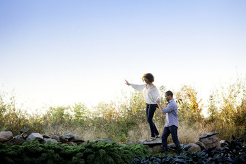 Boyfriend supporting girlfriend walking on top of stone abuttal