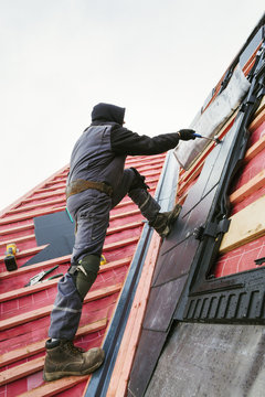 A roofer replacing the tiles on a house roof. 